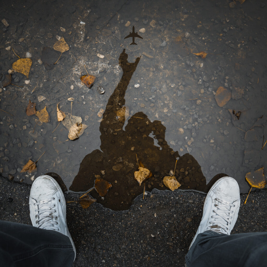 Person wearing white low top shoes taking photo of water